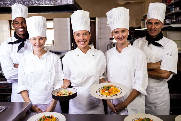 在酒店的厨房里举行准备好的意大利面的厨师团体 — 图库照片