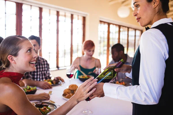 在餐厅的餐桌上向顾客展示葡萄酒的服务员 — 图库照片