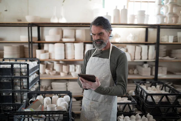 Potter Koncentruje Się Przy Użyciu Tabletu Otoczony Pracy Pracowni Ceramiki — Zdjęcie stockowe