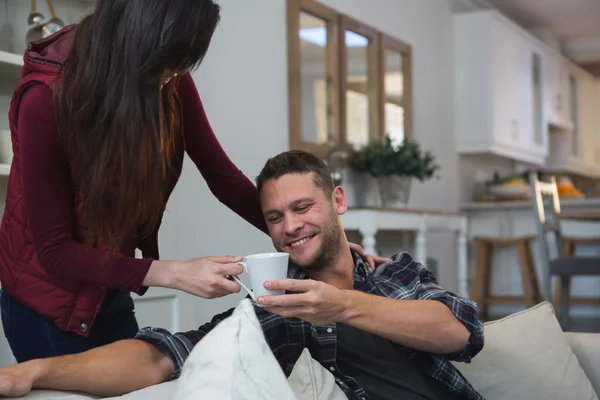 自宅のリビング ルームで男性に一杯のコーヒーを与える女性 — ストック写真