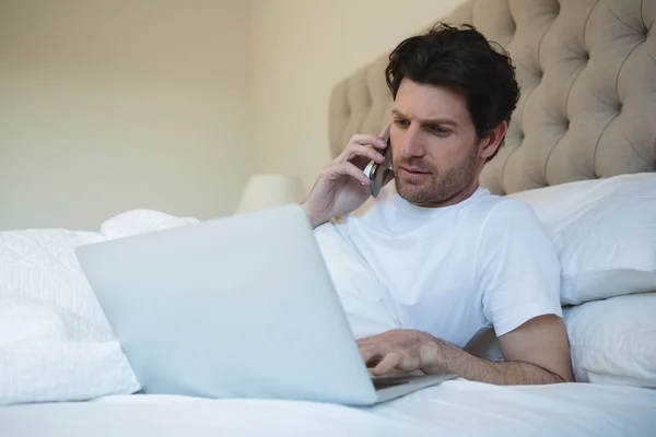 Man Using Laptop While Talking Mobile Phone Home — Stock Photo, Image