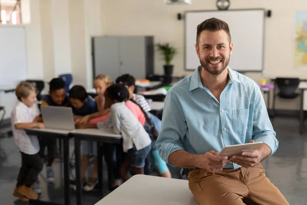 Profesor Feliz Con Tableta Digital Mirando Cámara Mientras Los Niños — Foto de Stock