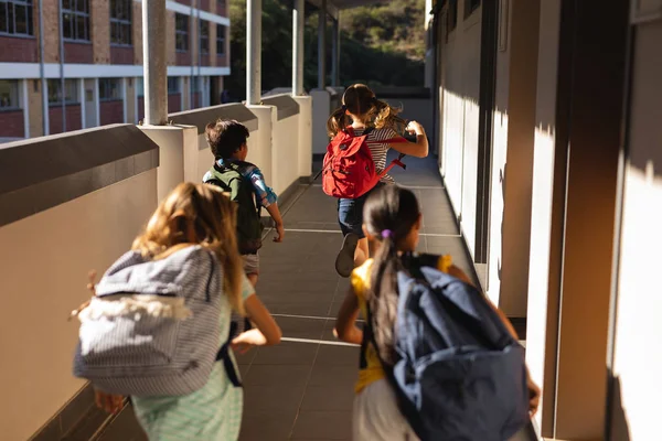 小学生在小学走廊上运行书包的后视 — 图库照片