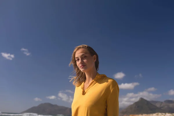 背景の山に対してビーチに立っている若い女性の肖像画 — ストック写真