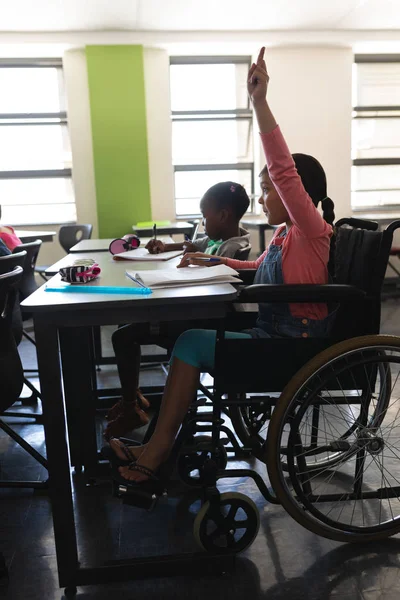 Vista Laterale Disabilitare Scolara Alzando Mano Seduto Alla Scrivania Classe — Foto Stock