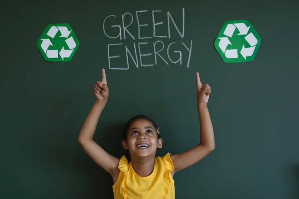 小学校の教室でのグリーン エネルギー基板に対して立っている腕の女子高生の笑顔のフロント ビュー — ストック写真