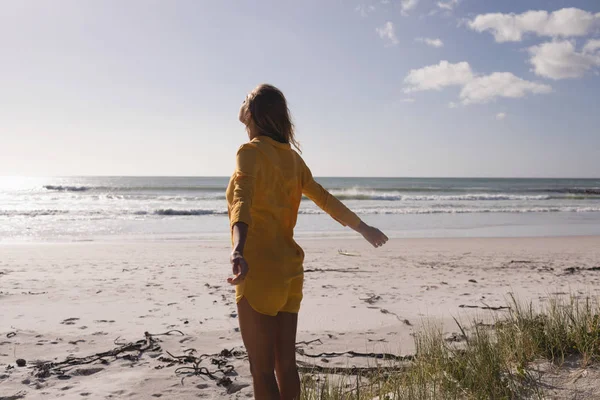 年轻女子站在沙滩上 伸出双臂望着大海 — 图库照片