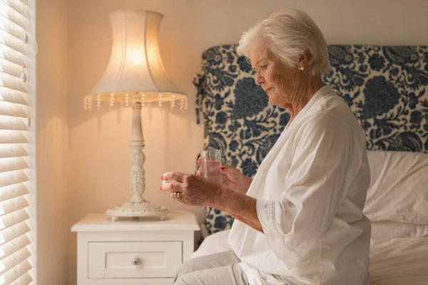 Вид Сбоку Пожилую Женщину Принимающую Лекарство Стаканом Воды Своей Спальне — стоковое фото