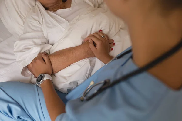 年配の女性を慰めると 自宅の寝室で彼女の腕を保持している女性医師の中央部 — ストック写真