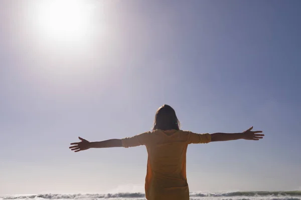 妇女站在海滩上的背景图 双臂伸直 对抗阳光 — 图库照片