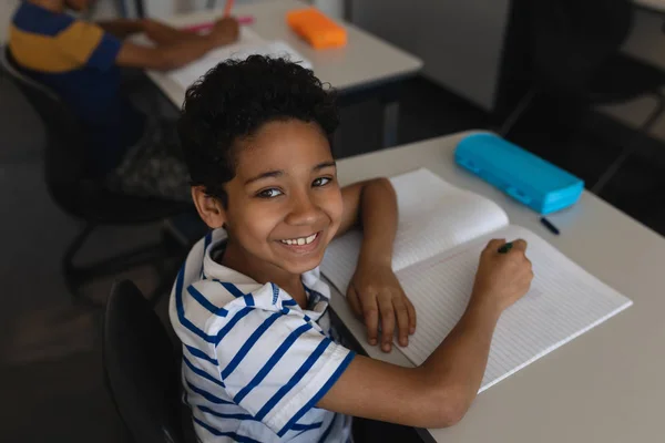 Schooljongen Glimlachend Camera Kijken Terwijl Het Bestuderen Klas Van Basisschool — Stockfoto