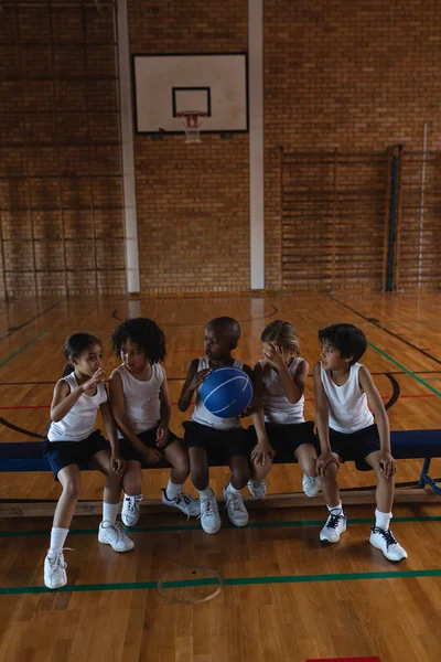 学校同学们在学校篮球场上交谈和坐在板凳上的正面看法 — 图库照片