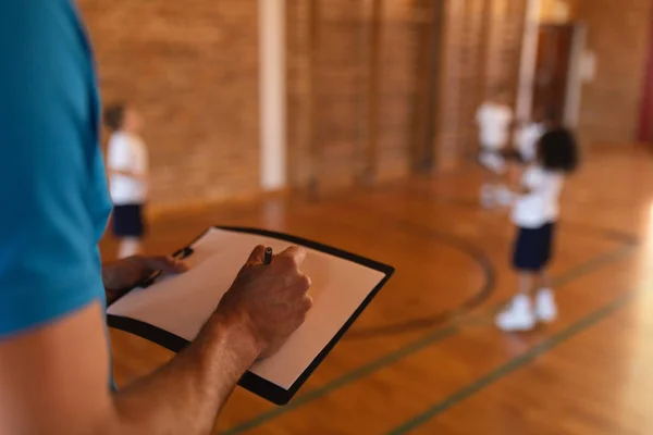 学校のバスケット ボール コートでクリップボードに書き込むバスケット ボールのコーチのクローズ アップ — ストック写真