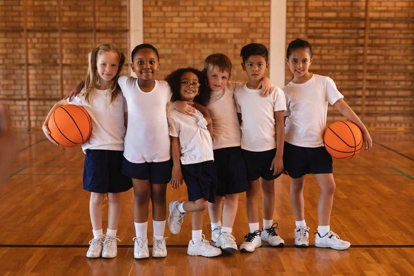 学校篮球场上小学生站着看镜头的正面看法 — 图库照片