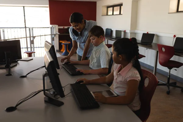 Zijaanzicht Van Vrouwelijke Leraar Leer Computer Schoolkid Bij Bureau School — Stockfoto