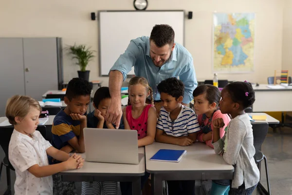 小学校の教室でのラップトップの子供たちを教える男性教師の正面図 — ストック写真