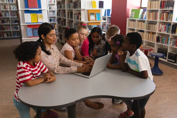 Zijaanzicht Van Vrouwelijke Leraar Lesgeven Nieuwsgierig Schoolkinderen Laptop Aan Tafel — Stockfoto
