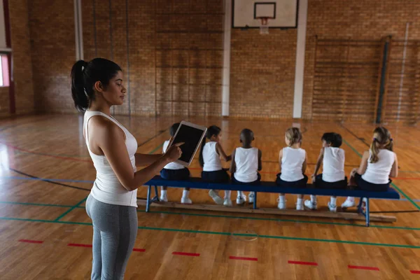 学校篮球场女篮教练使用数字平板电脑的侧视图 — 图库照片