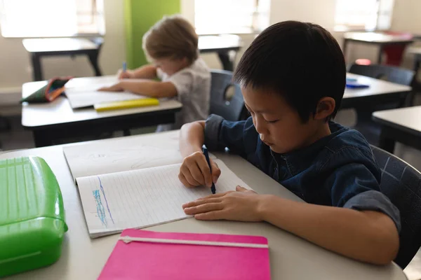 学校の机に座っている教室で勉強集中少年の側面図 — ストック写真