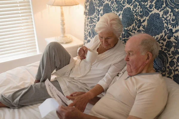 Side View Senior Couple Reading Newspaper Drinking Bed Home — Stock Photo, Image