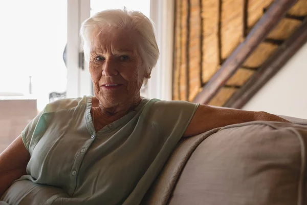 自宅のリビング ルームでソファの上でリラックスした年配の女性の肖像画 — ストック写真