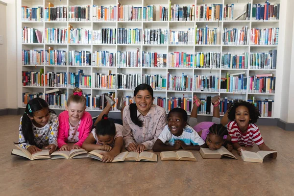 Visão Frontal Professoras Alunas Lendo Livro Enquanto Estavam Deitadas Chão — Fotografia de Stock