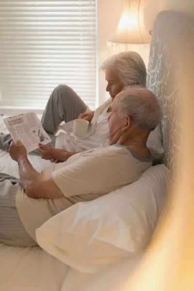 Side View Senior Couple Reading Newspaper Drinking Bed Home — Stock Photo, Image