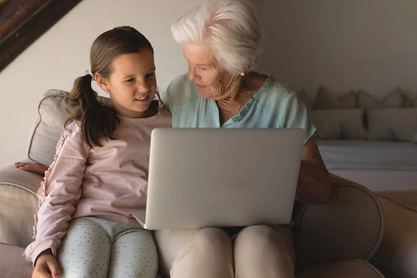 祖母和孙女在家里的客厅里讨论笔记本电脑的正面看法 — 图库照片