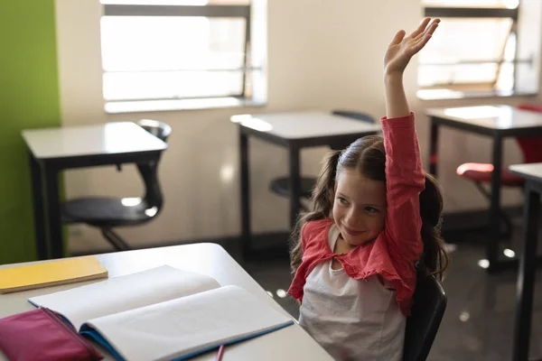 笑顔の女子高生の教室で机に座っている間は挙手の側面図 — ストック写真