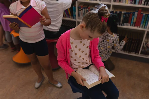 Vista Frontal Colegiala Leyendo Libro Sentada Silla Biblioteca Escuela — Foto de Stock