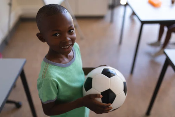 Sobrecarga Del Colegial Sonriente Sosteniendo Fútbol Aula Escuela Primaria — Foto de Stock