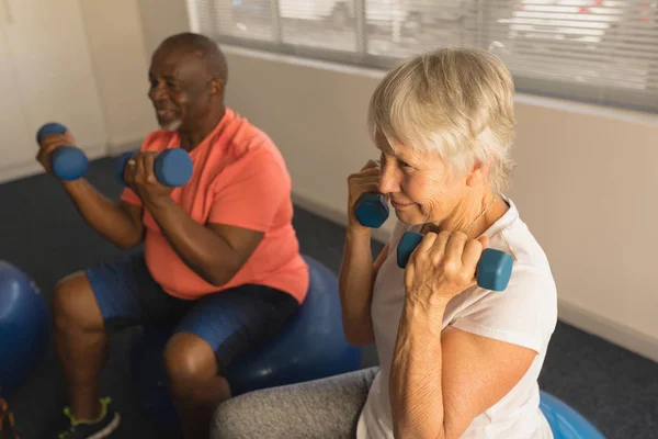 活跃的老年人在家里用哑铃锻炼的侧视图 — 图库照片