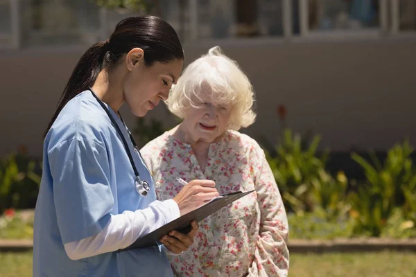 Vista Lateral Joven Doctora Discutiendo Informe Médico Con Mujer Mayor — Foto de Stock