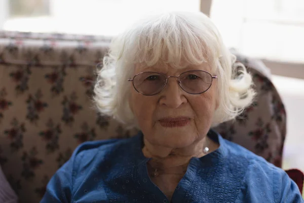 年配の女性が座っていると 特別養護老人ホームでのカメラ目線の正面図 — ストック写真