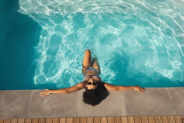年轻混血女子的高视角 太阳镜靠在家里后院的泳池边 — 图库照片