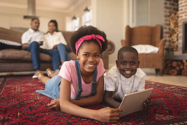 デジタル タブレットの床に横たわっていると 快適な家でカメラを見て幸せのアフリカ系アメリカ人兄弟の肖像画 — ストック写真