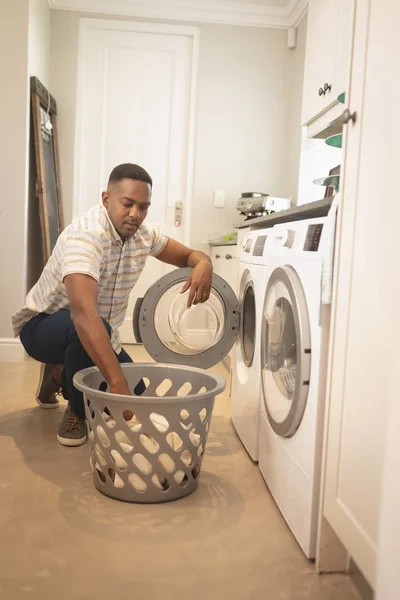 自宅の洗濯機で洗濯するアフリカ系アメリカ人の正面図 — ストック写真
