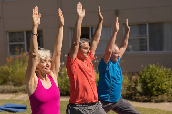 トレーナー トレーニングを公園で手の運動を実行することで高齢者の側面図 — ストック写真