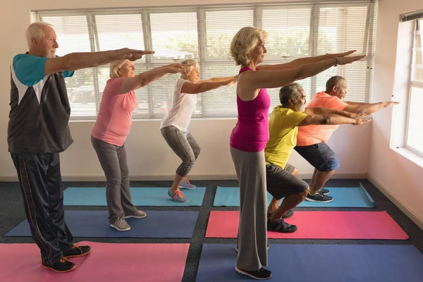 ヨガマットを自宅で運動を実行するアクティブな高齢者のグループの側面図 — ストック写真