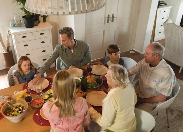 自宅のダイニング テーブルで食事しながらお互いの対話多世代家族の背面図 — ストック写真