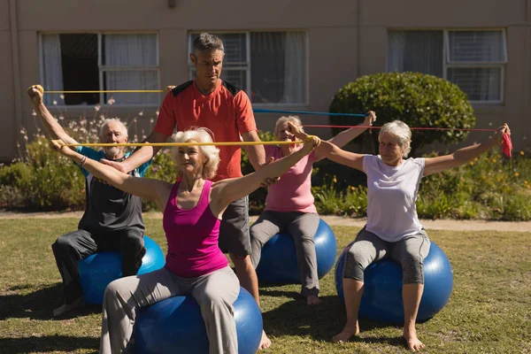 Вид Спереди Тренера Помогающего Пожилым Женщинам Выполнять Упражнения Эластичной Лентой — стоковое фото