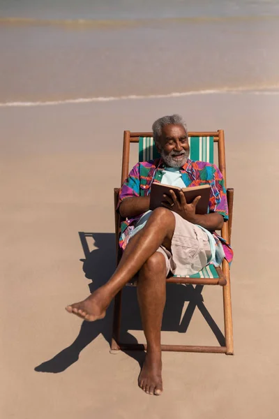 Vista Alto Ângulo Homem Sênior Relaxando Espreguiçadeira Lendo Livro Praia — Fotografia de Stock