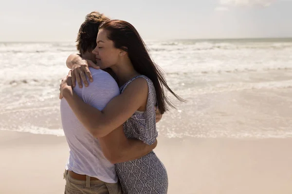 太陽の下 ビーチで抱き合ってロマンチックな若いカップルの側面図 — ストック写真
