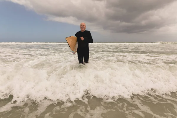 サーフボードとビーチで実行されているアクティブな年配の男性のフロント ビュー — ストック写真