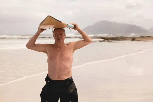 Čelní Pohled Aktivní Starší Muž Nesoucí Surfovací Prkno Jeho Hlavu — Stock fotografie