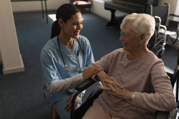 在养老院与残疾老年妇女交谈的快乐女医生的正面看法 — 图库照片