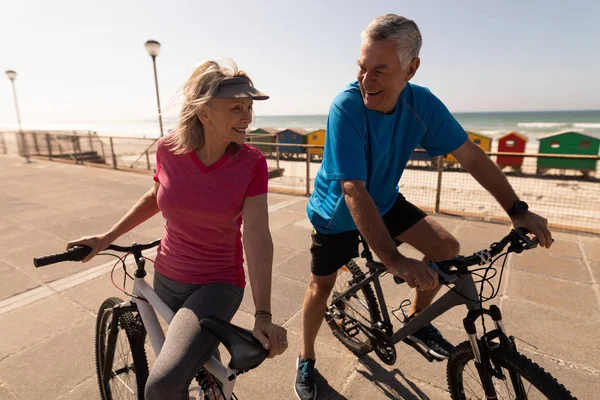 活跃的高级夫妇骑自行车在海滩的长廊上 — 图库照片