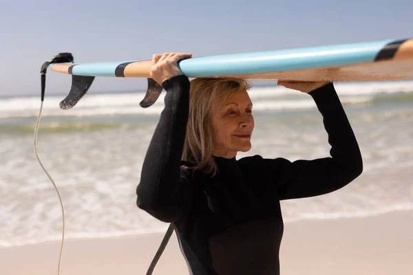 Zijaanzicht Van Actieve Senior Vrouwelijke Surfer Uitvoering Surfplank Haar Hoofd — Stockfoto