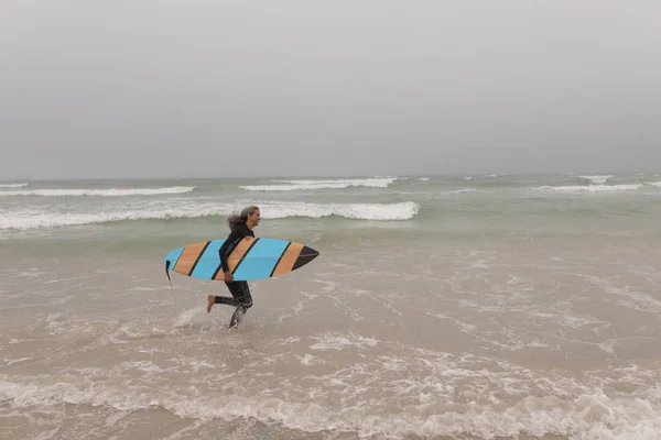 Side View Senior Female Surfer Surfboard Running Beach — Stock Photo, Image