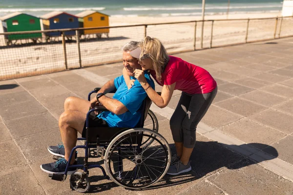 活跃的老年妇女在长廊艺术海滩上与残疾老年男子互动的侧视图 — 图库照片